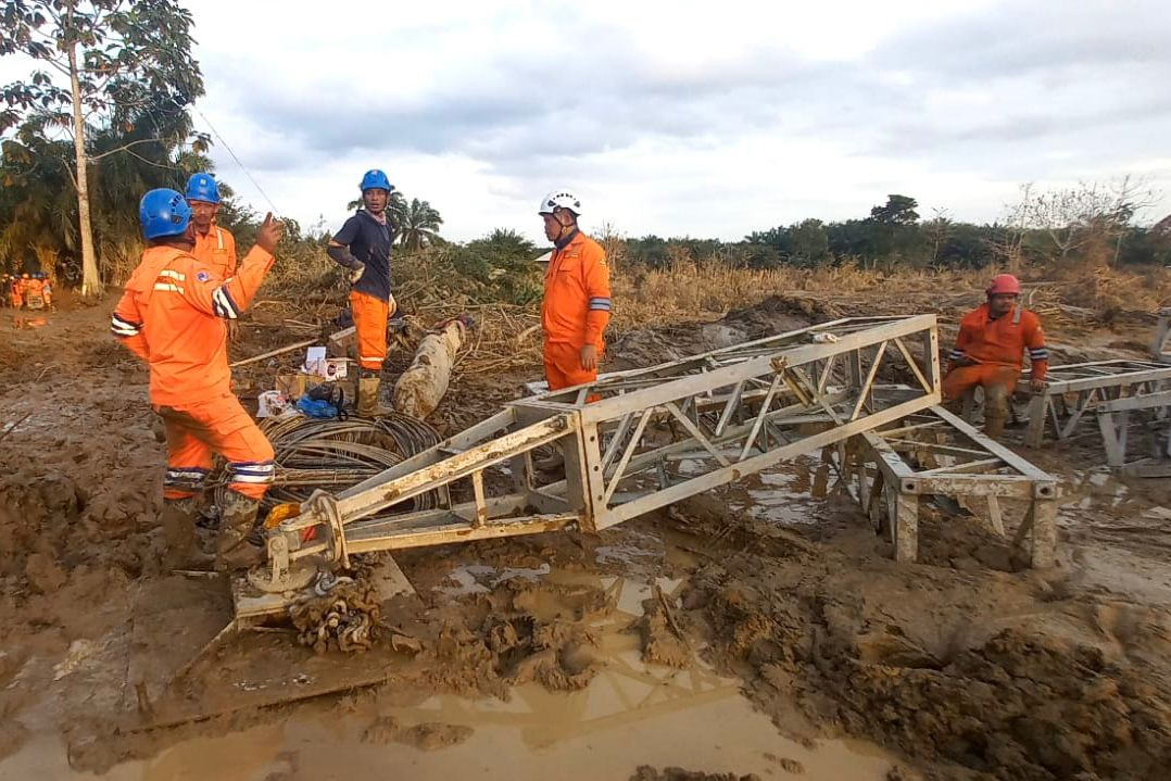 Di tengah medan yang berlumpur, petugas PLN melakukan perakitan menara darurat di jalur transmisi Langsa-Pangkalan Brandan.