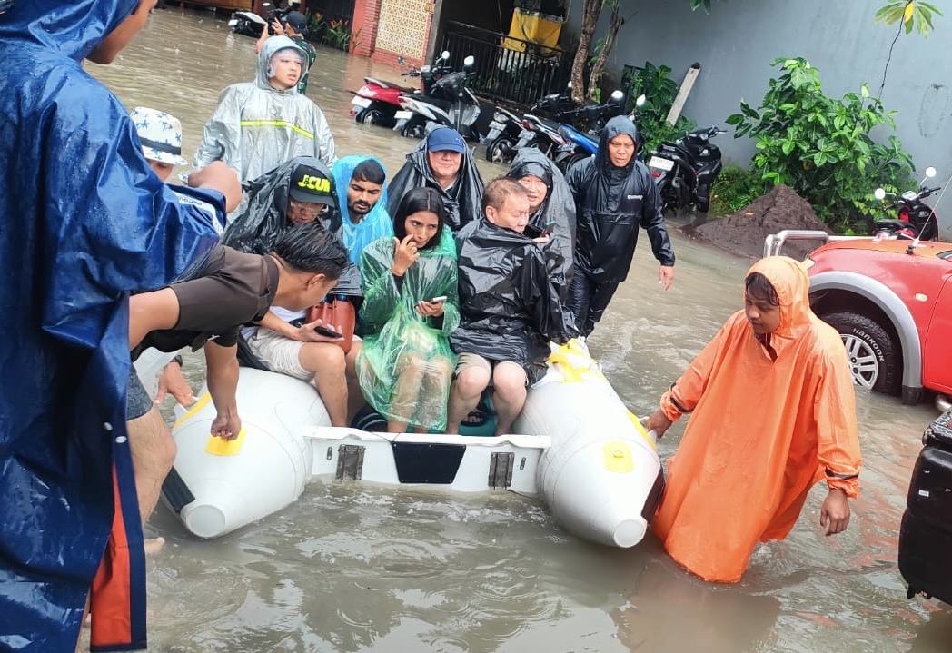 Petugas mengevakuasi warga korban banjir di Denpasar, Bali, Ahad (14/12/2025).