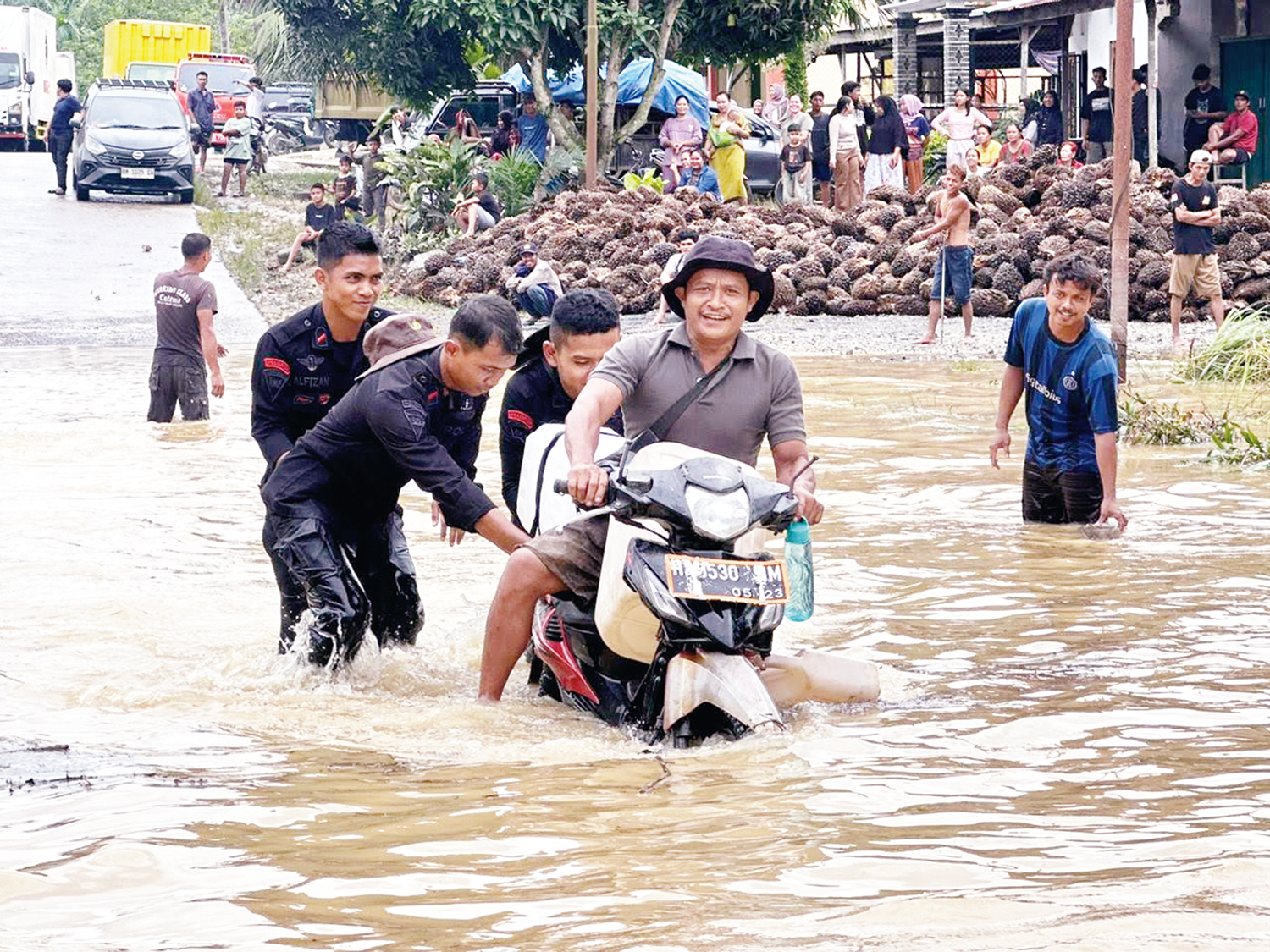 Personel Satbrimob Polda Riau Batalyon C Pelopor bersama Polsek Batang Gansal membantu pengendara yang sepeda motornya mogok  saat melintasi Jalan Lintas Timur yang dibanjiri luapan air Sungai Akar.
