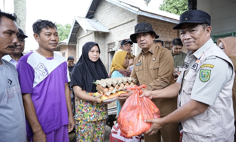 Sekdab Kabupaten Inhu, Zulfahmi Adrian didampingi Kepala KPBD Inhu, Mulyadi saat menyerahkan bantuan sembako kepada warga terdampak banjir di Desa Sungai Akar, Senin (15/12/2025).
