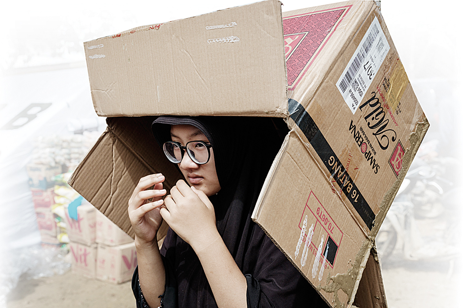 seorang wanita membawa kardus saat menunggu bantuan yang disumbangkan secara pribadi di daerah yang terkena banjir bandang di Aceh Tamiang, Ahad (14/12/2025).