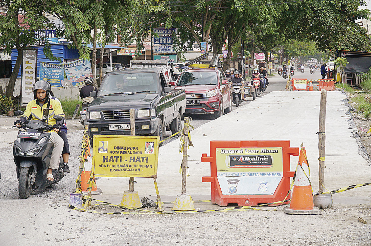 Pengendara melintas di Jalan Dharma Bakti, Kecamatan Payung Sekaki yang sedang diperbaiki dengan sistem semenisasi oleh Pemko Pekanbaru, Senin (15/12/2025).