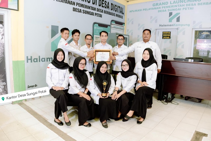 Kepala Desa Sungai Petai Rian Adli (belakang dua dari kiri) bersama perangkat Pemdes Sungai Petai memperlihatkan piala dan sertifikat juara Inovasi Daerah Kabupaten Kampar 2025, Selasa (16/12/2025).