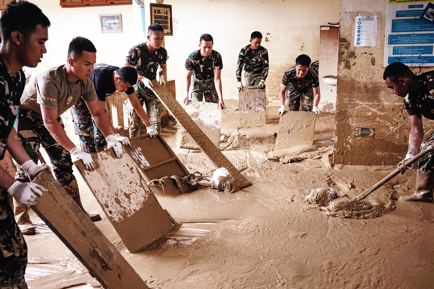Tentara Nasional Indonesia dari YONIF TP 853/BRB, Aceh Timur, membersihkan lumpur di Rumah Sakit Daerah di Aceh Tamiang, Nanggroe Aceh Darussalam, Selasa (16/12/2025) setelah banjir bandang,  beberapa waktu lalu.
