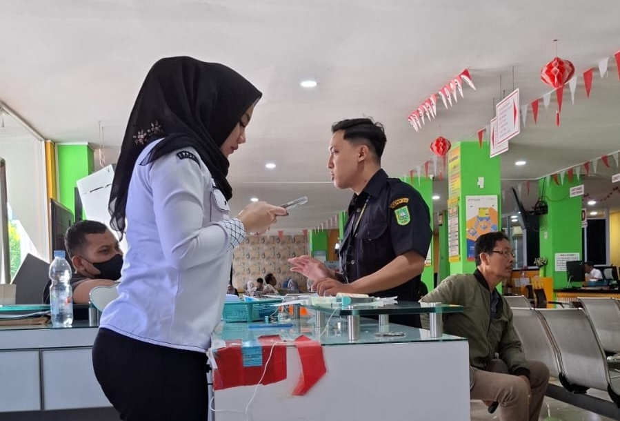 Petugas bagian pendaftaran Samsat Gajah Mada Pekanbaru membantu memeriksa berkas pembayar pajak agar segera diproses, baru-baru ini.