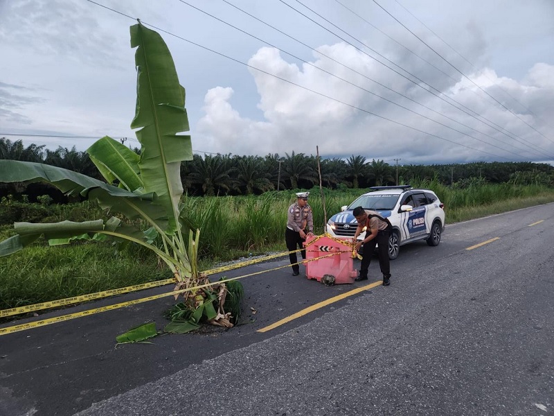 Personel Satlantas Polres Siak memasang water barrier dan garis polisi di jalan dengan lubang menganga di Jalan Lintas Dayun&ndash;Perawang KM 57, di Desa Sawit Permai, Kecamatan Dayun, Kabupaten Siak.