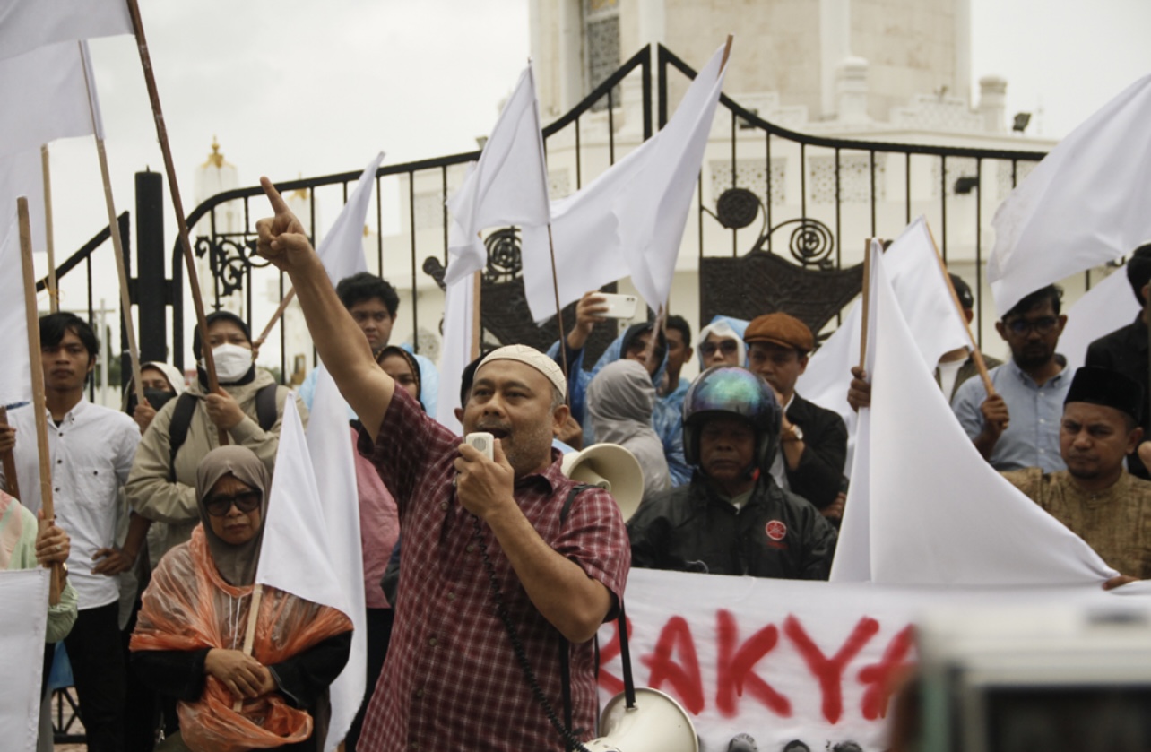 Koalisi Masyarakat Sipil Aceh Peduli Bencana Sumatera menggelar aksi dan mengibarkan bendera putih, di depan Masjid Raya Baiturrahman, Banda Aceh, Kamis (18/12/2025).