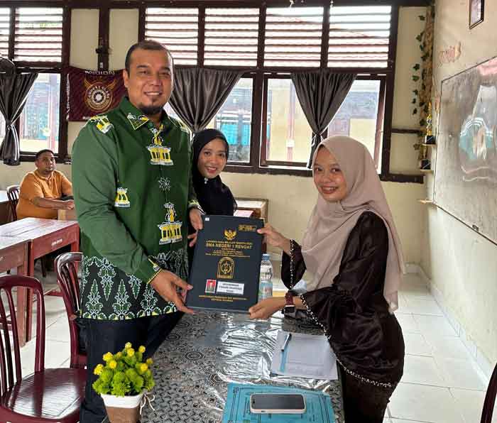 Bupati Inhu Ade Agus Hartanto didampingi istri Suci Rahmiani menerima rapor anak dari wali kelas di SMAN 1 Rengat, Jumat (19/12/2025).