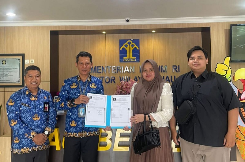 Kepala Divisi Pelayanan Hukum Kanwil Kemenkum Riau Febri Mujiono menyerahkan dokumen Petikan Resmi Pendaftaran Merek Dagang kepada seorang pemiliknya pada Senin (22/12/2025),