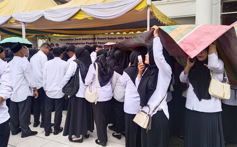 PPPK Paruh Waktu berteduh mengunakan terpal, disela kegiatan penyerahan SK di depan kantor BPKAD Rohil di Bagansiapiapi, Rabu (24/12/2025).