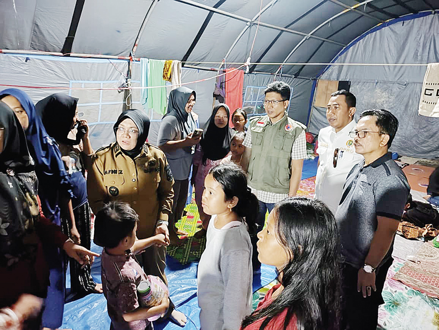 Bupati Siak Afni, didampingi Kalaksa BPBD Siak Novendra berbincang dengan warga saat mengunjungi tenda pengungsian di Kampung Dosan, Kecamatan Pusako yang terdampak banjir, Senin (22/12/2025) malam.