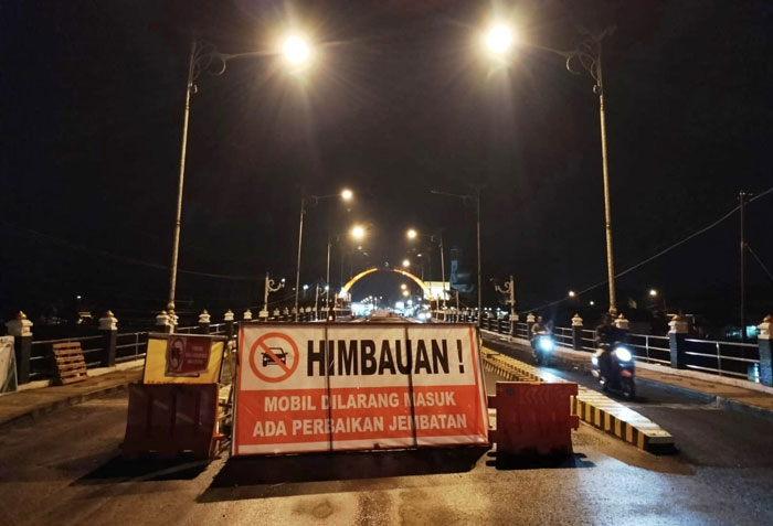 Lampu hias menerangi Jembatan Sungai Batang Lubuh I Pasirpengaraian yang masih diberlakukan penutupan sebagian. Kendaraan roda dua melintas lewat jalur kiri dan kanan, jalur tengah masih ditutup.