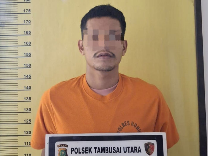 Tersangka AS (25) dalam kasus tindak pidana kekerasan secara bersama-sama diamankan di Mapolsek Tambusai Utara, Jumat (26/12/2025).