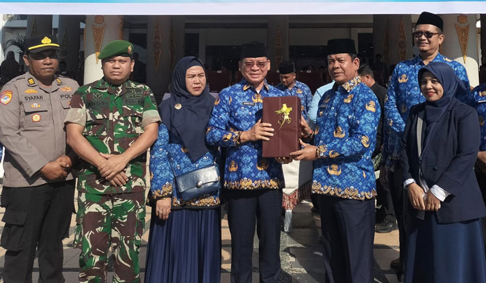 Wabup Rohul H Syafaruddin Poti (kanan) serahkan SK Pensiun dan cendramata kepada Kadisdikpora Rohul H Damri Poti, usai upacara peringatan HUT ke 54 Korpri di halaman Kantor Bupati Rohul baru-baru ini