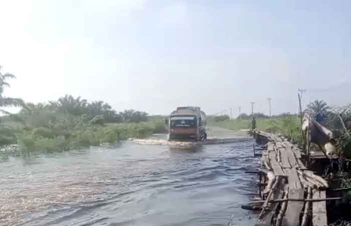 : Truk milik perusahaan perkebunan melintasi genangan air yang merendam jalan provinsi di Desa Sontang Bonai Darussalam Kabupaten Rokan Hulu batas Duri Kabupaten Bengkalis, Jumat (2/1/2026).