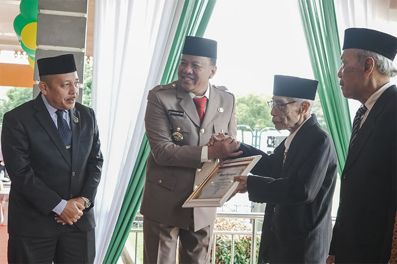 Bupati H Suhardiman Amby menyerahkan cendera mata pada Drs H Mukhtar Samad mantan Kanwil Kemenag Riau asal Kuansing usai upacara peringatan HAB Kemenag, Sabtu (3/1/2026) di Lapangan Limuno