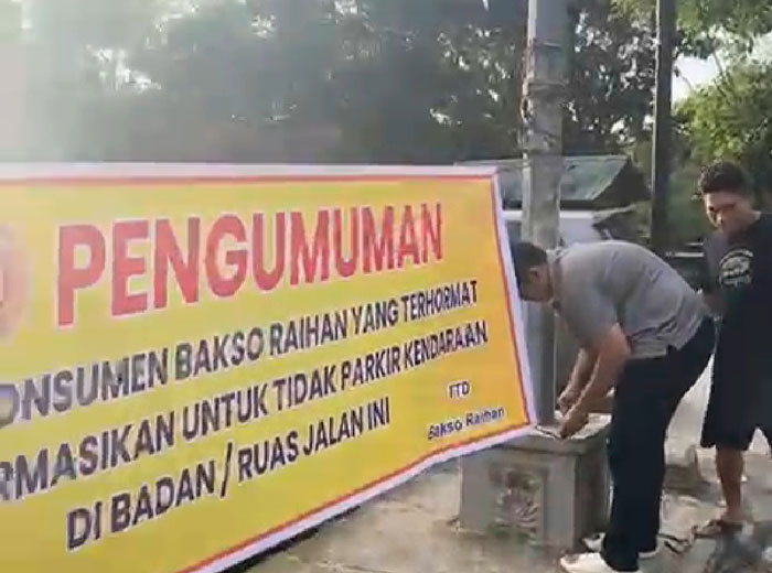 Petugas tengah memasang spanduk imbauan agar kendaraan tidak parkir di badan Jalan Datuk Setia Maharaja/Parkir Indah tepatnya di depan Bakso Raihan, Sabtu (3/1/2026).