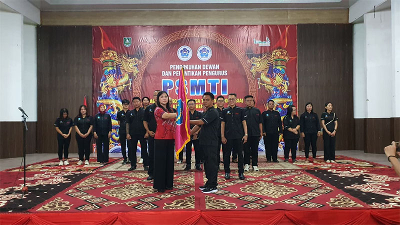 Plt Ketua PSMTI Riau Lindawati menyerahkan bendera pataka kepada Ketua PD PSMTI Bengkalis Tengdy Wijaya, Ahad (4/1/2026) malam.