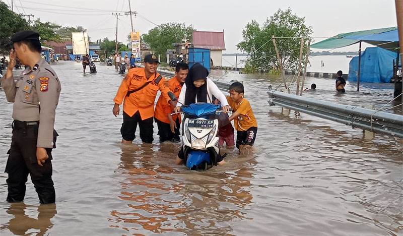 Masyarakat mendorong sepeda motor akibat mogok setelah melewati jalan banjir di Jalan Provinsi, Parit 6, Tembilahan Hulu, Inhil, Selasa (6/1/2026).