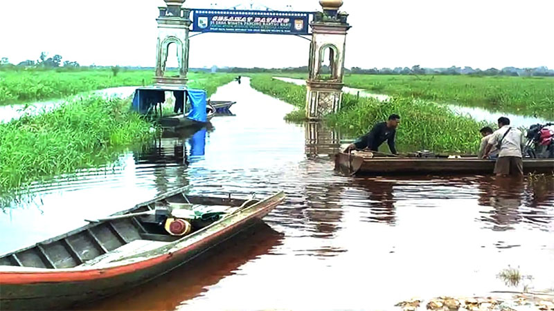 Masyarakat Desa Rantau Baru melakukan aktivitas menggunakan sampan akibat akses jalan desa mereka mulai direndam banjir, Kamis (8/1/2026).