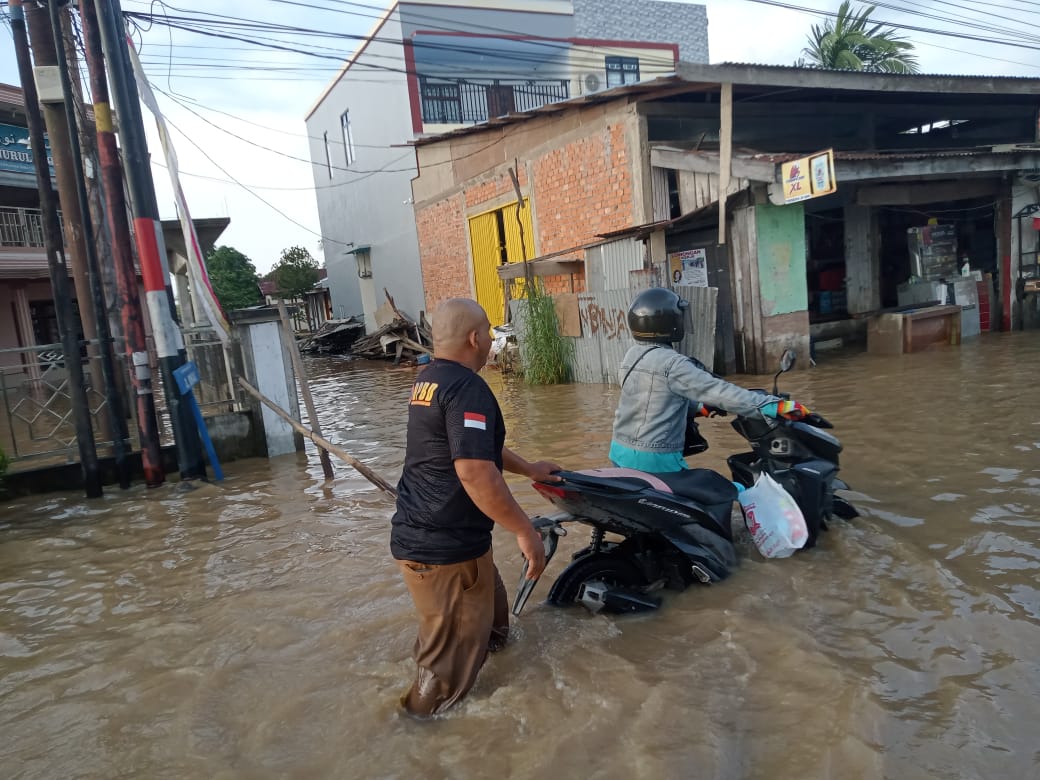 Pengendara mendorong sepeda motornya yang mogok saat melintasi jalan yang tergenang air pasang rob di wilayah Tembilahan, kemarin.