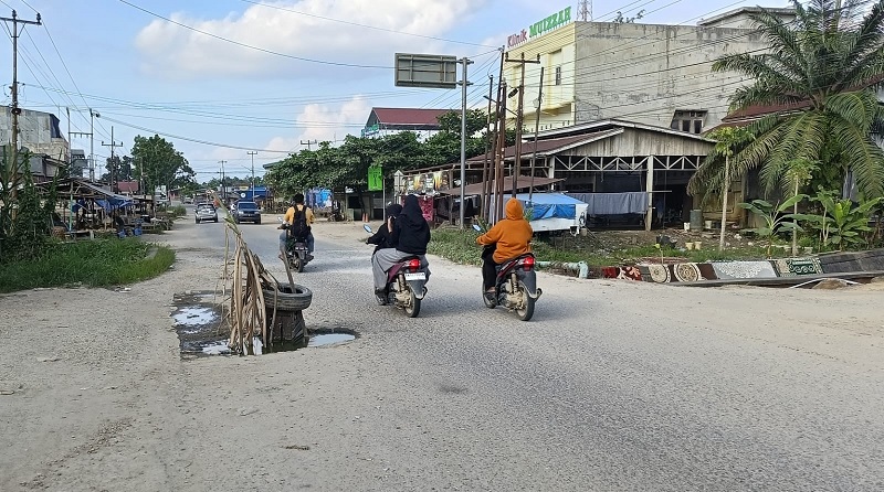 Warga saat melintas di Jalan Pematang Reba-Pekan Heran yang mengalami rusak, Selasa (13/1/2026).