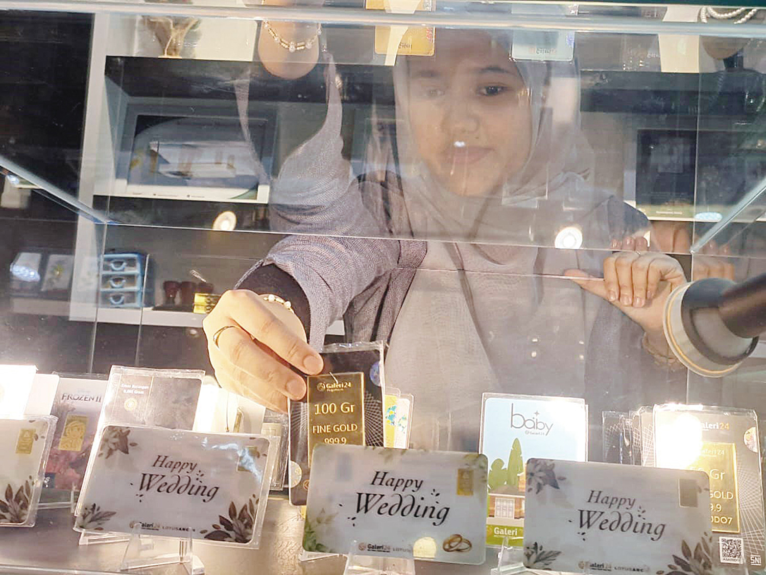 Seorang petugas di Galeri 24 Pekanbaru memperlihatkan emas batangan yang mengalami kenaikan harga, Selasa(13/1/2026).