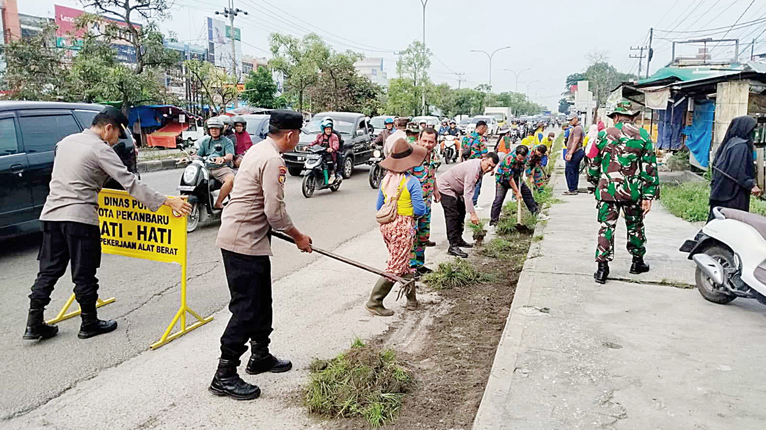 Anggota Kepolisian bersama Petugas PUPR kota dan rekanan melaksanakan gotong royong di sepanjang Jalan Soebrantas Panam Pekanbaru, Rabu (14/1/2026).