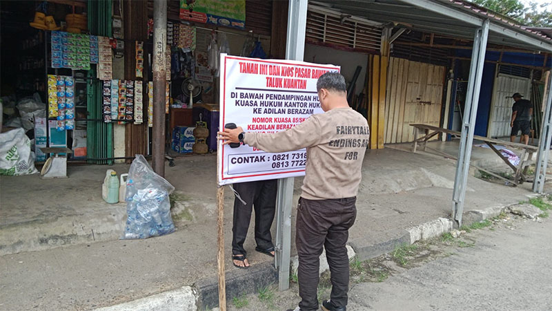 Pemilik kios Pasar Bawah Teluk Kuantan memasang spanduk di lokasi Pasar, Kamis (15/1/2026) sore.