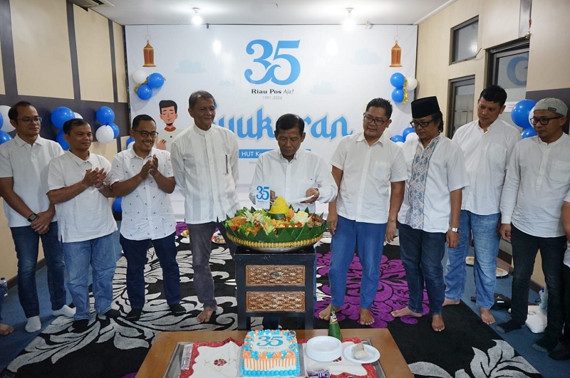 Wakil Komisaris Utama Riau Pos Amril Noor disaksikan Komisaris Raznizal Syukur, Dirut Riau Pos Ahmad Dardiri, Direktur Firman Agus, Direktur Asmawi Ibrahim serta jajaran direksi potong tumpeng.