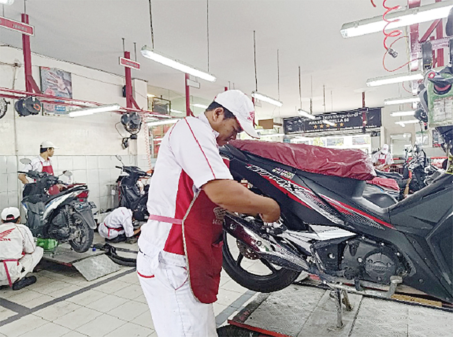 Seorang pekerja sedang melakukan servis motor Honda di sebuah bengkel, belum lama ini.