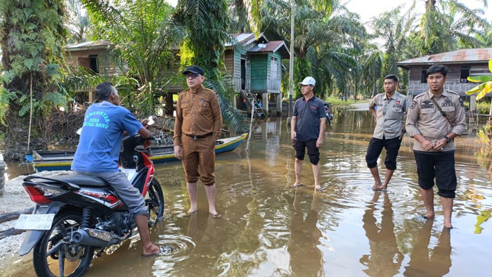 Kalaksa BPBD Pelalawan, Zulfan MSi meninjau banjir yang menggenangi badan jalan Desa Rantau Baru Kecamatan Pangkalan Kerinci yang mulai mengalami penyusutan, Senin (19/1/2026).