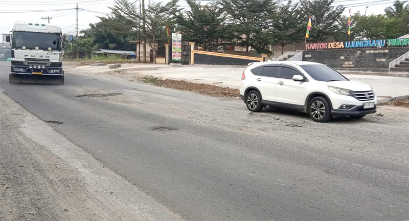 Mobil berat berusaha menghindari jalan rusak di depan Kantor Desa Ujung Batu Timur, Kecamatan Ujung Batu, Rohul, Selasa (20/1/2026).