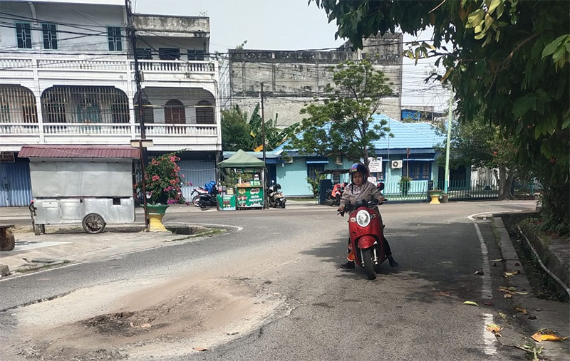 Pengendara sepeda motor melintas di jalan rusak yang baru ditimbun dengan tanah di Kota Bengkalis
