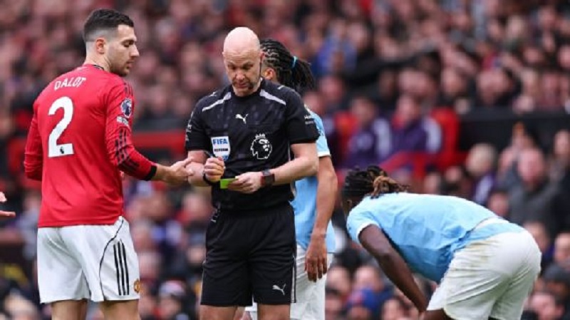 Anthony Taylor memberikan kartu kuning kepada Diogo Dalot dari Manchester United atas tekelnya terhadap Jeremy Doku dalam Derbi Manchester pada hari Sabtu di Old Trafford.