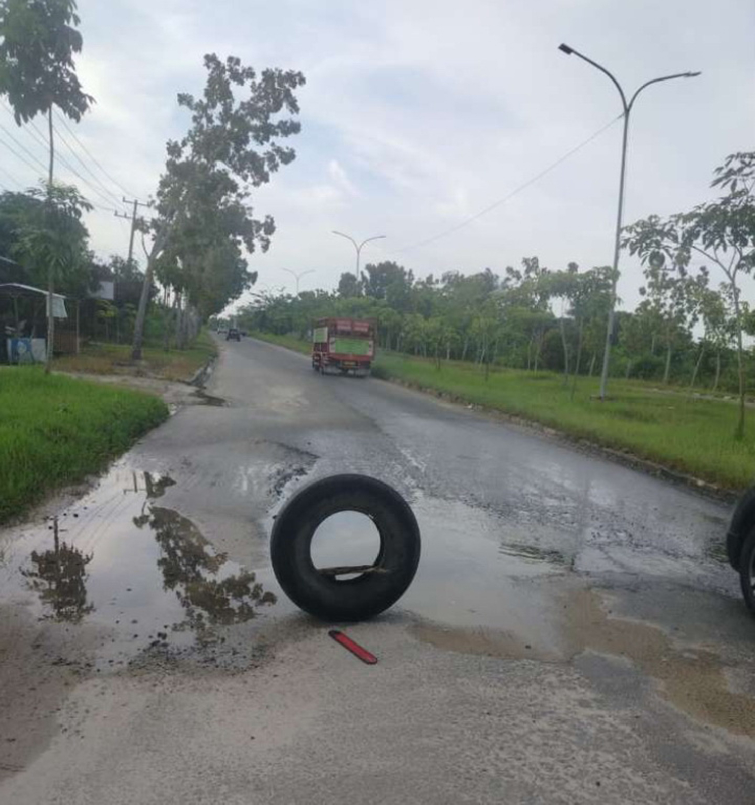 Masyarakat memasang ban di tengah badan Jalan Abdul Jalil Pangkalankerinci yang banyak berlubang dan belum dilakukan perbaikan oleh Dinas PUPR Pelalawan, Rabu (21/1/2026).