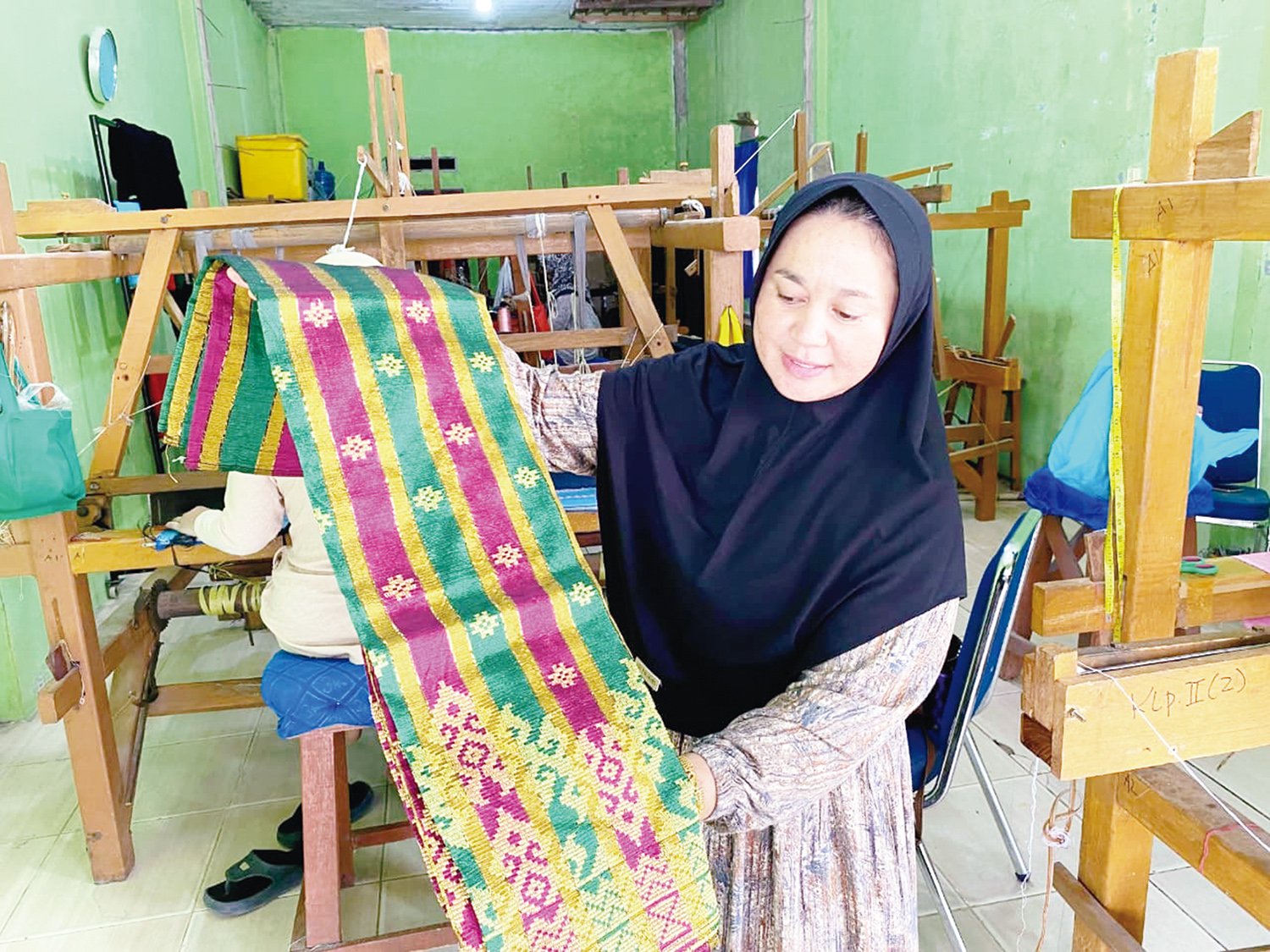 Ketua Kelompok Usaha Rumah Tenun Pulau Payung Kabupaten Pelalawan Yulhendra memperlihatkan kain tenun hasil produksi mereka, baru-baru ini.