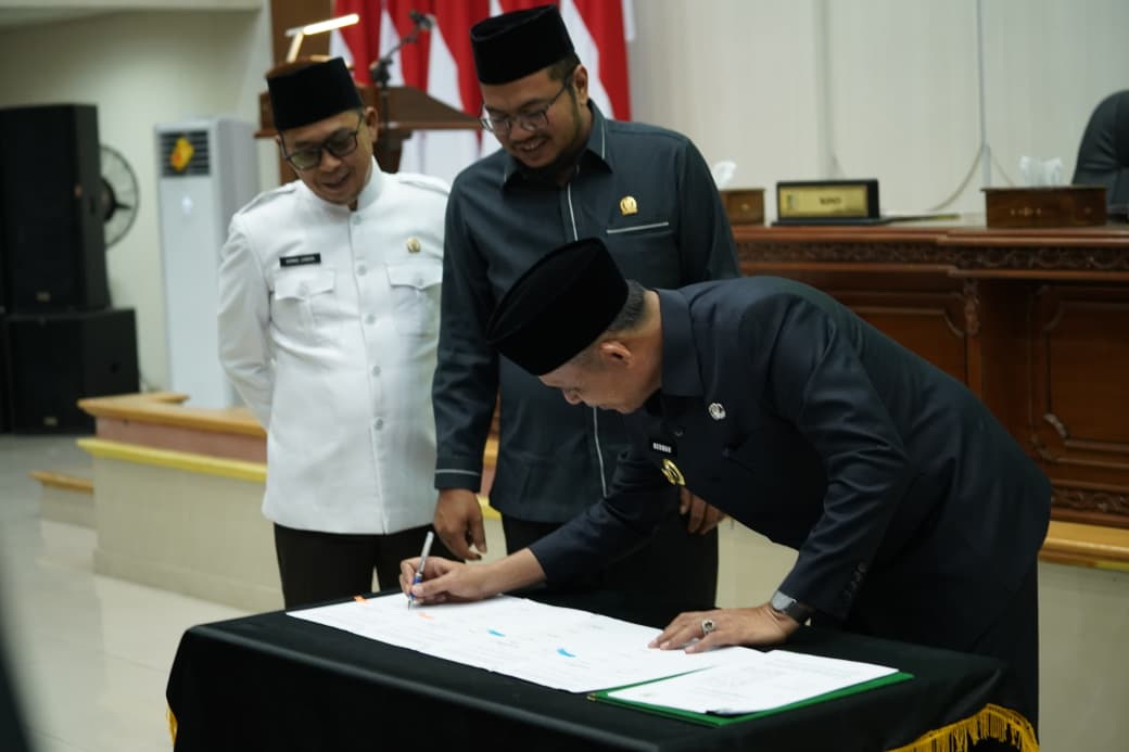 Bupati Inhil, Herman, menandatangani dokumen disaksikan Ketua DPRD Inhil Iwan Taruna dan Wakil Ketua Ahmad Junaidi usai Rapat Paripurna Pengesahan APBD Inhil tahun 2026 di gedung DPRD Inhil,