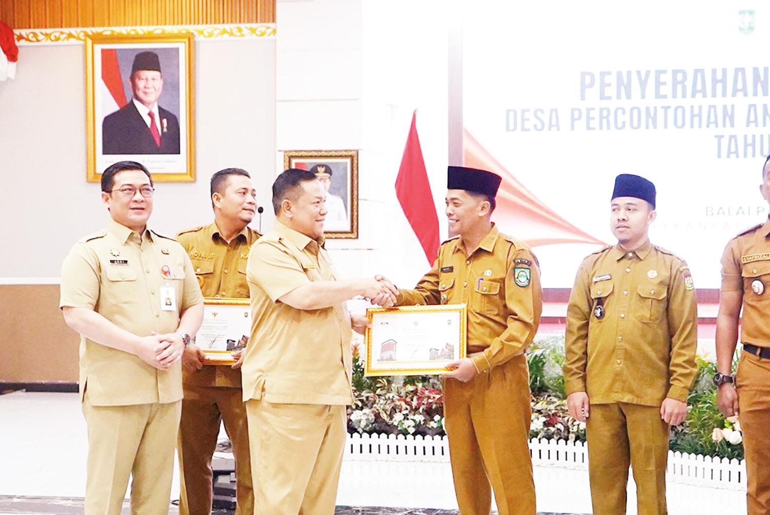 Pelaksana Tugas Gubernur Riau SF Hariyanto menyerahkan piagam penghargaan kepada perwakilan Desa Percontohan Antikorupsi Provinsi Riau tahun 2025 di Gedung Daerah Riau, Senin (26/1/2026).