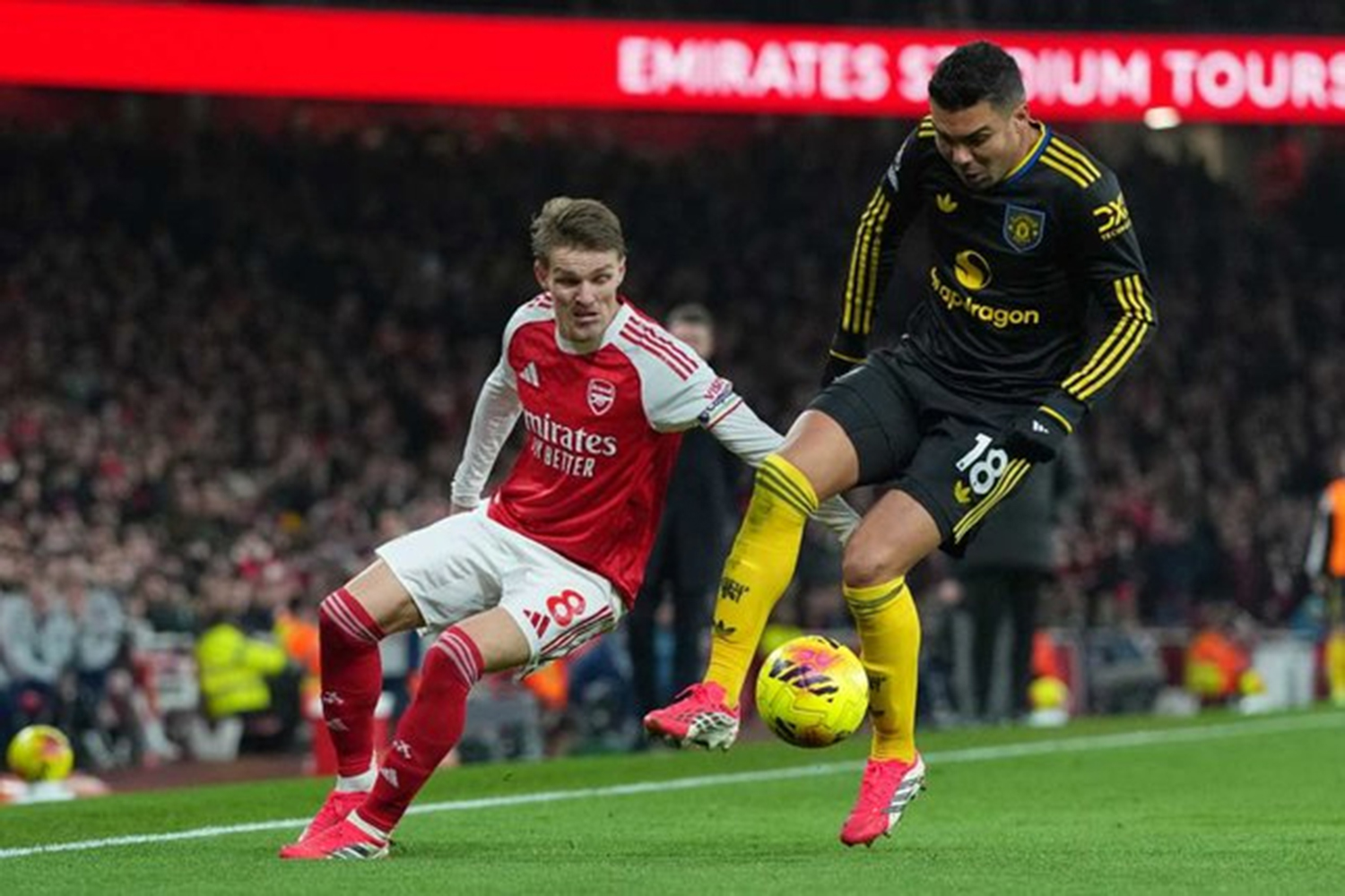 Pemain Manchester United Casemiro (kanan) mengawal bola dari pemain Arsenal Martin Odegaard dalam pertandingan Premier League, Ahad (25/1/2026).