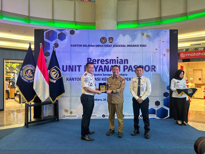 Wawako Pekanbaru Markarius Anwar menerima plakat penghargaan dari Kepala Kantor Imigrasi Kelas I TPI Pekanbaru Ryang Yang Satiawan (kiri), usai meresmian ULP di Mal Ciputra Seraya Pekanbaru.