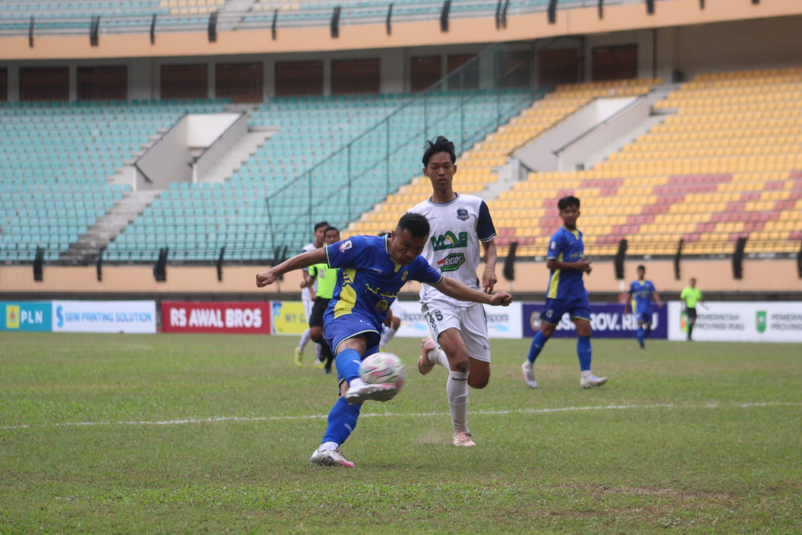 Pemain PS Siak, Sojanolo Zendrato (kiri), diadang pemain PSC Young Abadi saat akan menendang bola dalam pertandingan RS Awal Bros Liga 4 Riau 2025/2026 di Stadion  Utama Riau, Selasa (27/1/2026).