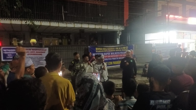 Perwakilan massa aksi menyaksikan penggembokan pintu depan New Paragon di Jalan Syarif Kasim, Kota Pekanbaru, Senin (2/2/2026) malam.