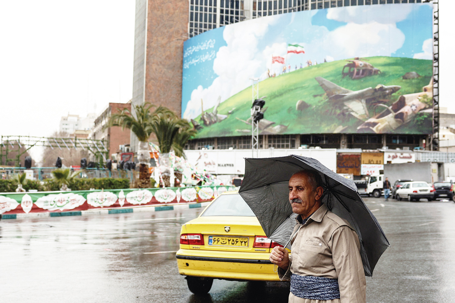 Seorang warga Iran dengan pakaian tradisional berjalan melewati papan reklame anti-AS yang terpampang pada gedung di Lapangan Valiasr, Teheran, Rabu (4/2/2025).