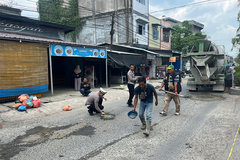 Kasat Lantas Polres Inhil AKP Ricki Marzuki bersama pihak lainnya melakukan penambalan lubang di Jalan Baharudin Yusuf Tembilahan, Selasa (10/2/2026).
