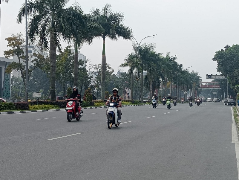 Pengendara motor di Jalan Jenderal Sudirman Pekanbaru terlihat menggunakan masker akibat kabut asap tipis mulai menyelimuti Kota Pekanbaru, Kamis (12/2/2026)
