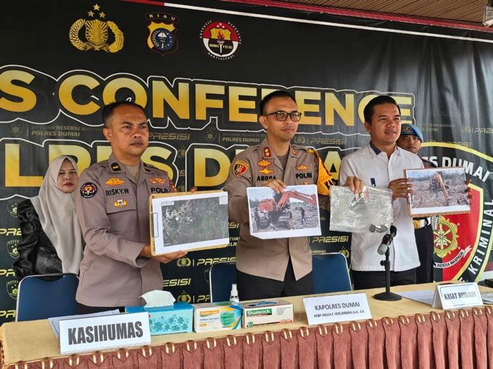 Kapolres Dumai AKBP Angga F Herlambang (tengah), didampingi Kasat Reskrim Polres Dumai AKP Agung Rama Setiawan (kanan), menunjukkan foto barang bukti alat berat saat ekspos, Kamis (12/2/2026)