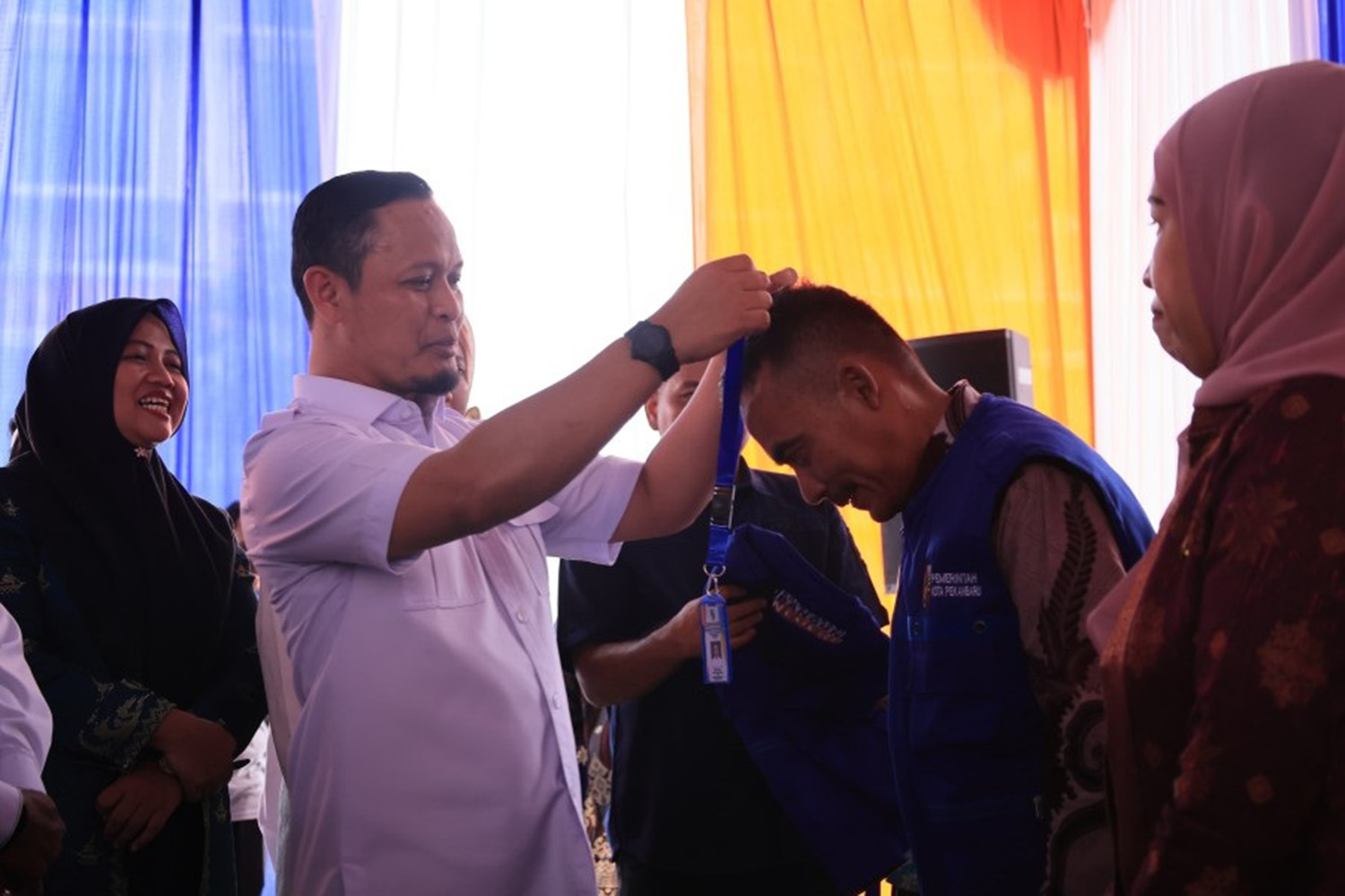 Wali Kota Pekanbaru Agung Nugroho memasangkan kartu tanda pengenal ke ASN dalam peresmian program Satu ASN Satu RW di Kantor Camat Binawidya, Kamis (12/2/2026).