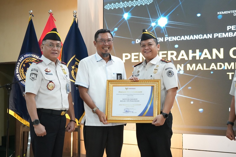 Disaksikan Kepala Kanwil Ditjen Imigrasi Riau Agung Prianto (kiri), Kepala Imigrasi Kelas I TPI Pekanbaru Ryang Yang Satiawan menerima penghargaan dari Kepala Ombudsman Perwakilan Riau Bambang Pratama
