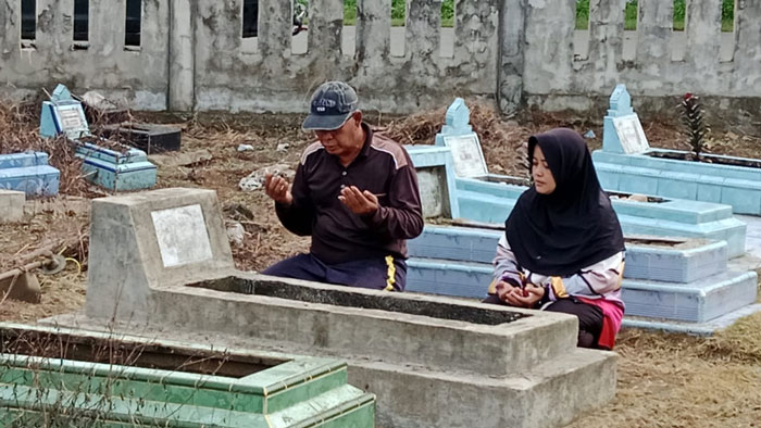 Isril bersama istri tengah memanjatkan doa di makam ibunya saat berziarah di pemakaman Dagang Simpang Tiga Teluk Kuantan, Selasa (17/2/2026) pagi.